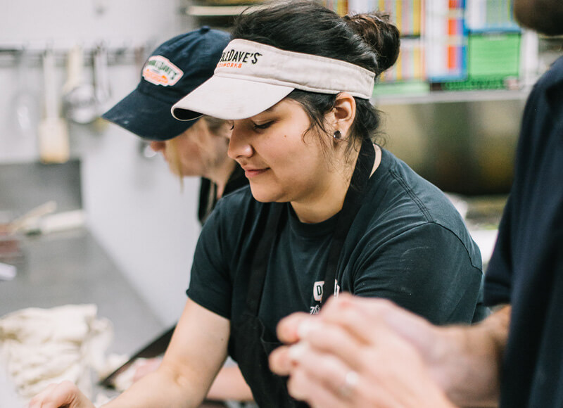 Smiling DoubleDave's employees prepares pizza