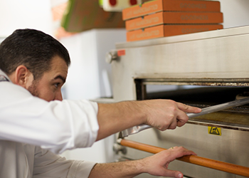 Chef putting pizza into the oven